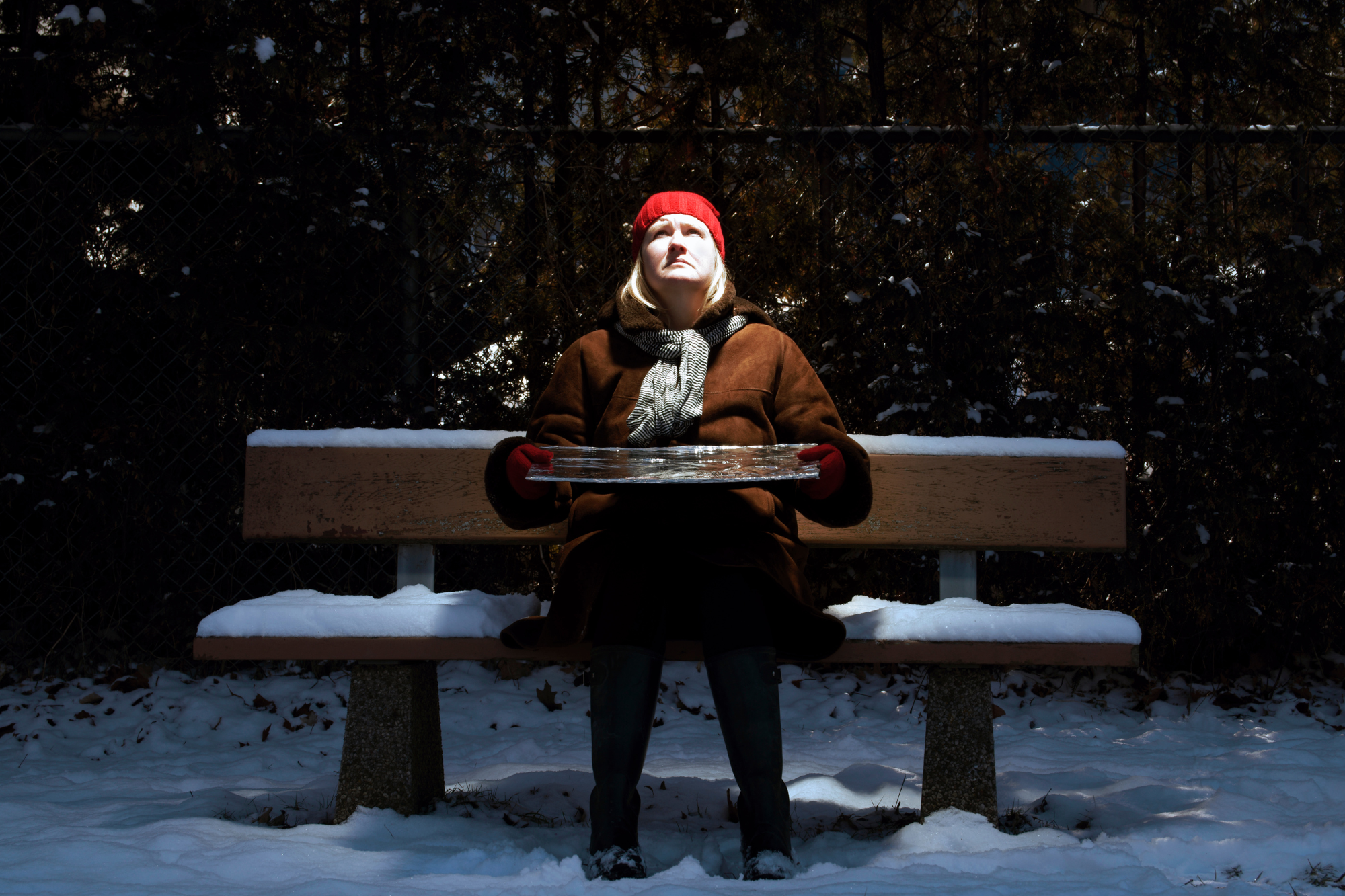 Woman sitting on a snowy bench trying to get sun to show how Seasonal Affective Disorder can lead to sadness
